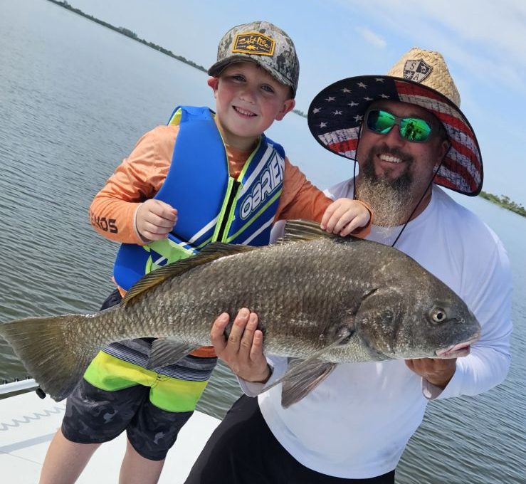 A man and child hold up a fish during an inshore fishing charter in Weeki Wachee FL